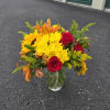 Bouquet of red roses, yellow daisies, and orange lilies in a glass vase