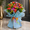 Bouquet of coral and pink roses with purple accents wrapped in blue paper