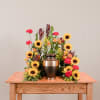 Sunflower and carnation funeral urn arrangement on a wooden table