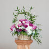 Basket arrangement of pink and white flowers with a leafy arch