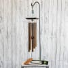 Copper wind chime hanging from a black stand
