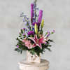 Pink lily arrangement with purple and blue flowers in a rustic wooden box