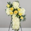 White floral cross with yellow roses on a stand