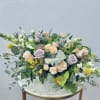 Mixed bouquet of pastel roses and yellow blooms in a decorative white vase