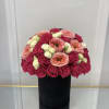 Round bouquet of pink, peach, and white roses in a black box