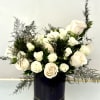 Arrangement of white roses with airy greenery in a tall black cylinder vase