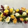 Yellow and white roses arranged in a white box with burgundy accents