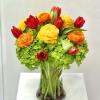 Bouquet of red, yellow, and orange flowers in a clear glass vase