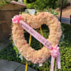 Peach floral heart wreath on an easel with pink ribbons