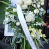 Standing funeral spray with white and pale yellow flowers on an easel
