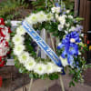 Large funeral wreath with white flowers and a blue memorial ribbon