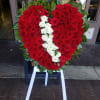 Heart-shaped red and white rose arrangement on an easel with white ribbon