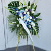 Tall standing floral spray with white roses, blue hydrangeas, and purple orchids