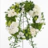 White and green floral wreath on a stand with orchids and roses