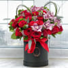 Red roses and pink orchids in a black hatbox with a red ribbon