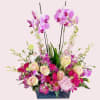 Pink and purple floral arrangement in a dark rectangular container