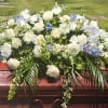 Large white floral casket spray with blue accents