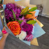Bouquet of purple chrysanthemums, orange lilies, and roses wrapped in blue paper