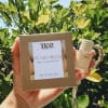 Hand holding a boxed soap bar and a small bottle outdoors