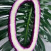 Purple-and-white floral lei on large tropical leaves
