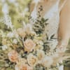 Bride holding a bouquet of peach and cream roses with airy dried accents