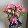 Pink roses and small pink blossoms in a glass vase with a ribbon