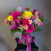 Colorful mixed bouquet in a glass vase with a pink ribbon