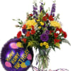 Mixed bouquet in a glass vase beside a purple happy birthday balloon.