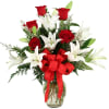 Bouquet of red roses and white lilies in a glass vase with a red ribbon