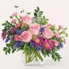 Pink roses and purple daisies in a clear glass vase