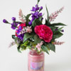 Pink and purple floral arrangement in a glass candle jar
