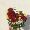 Bouquet of red roses and yellow tulips in a glass vase