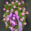 Pink rose and carnation funeral spray with a purple ribbon