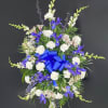 Standing floral spray with white and purple flowers and a blue ribbon