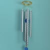 Hanging wind chime with blue fish, silver tubes, and blue crystal drop on a teal wall