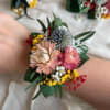 Floral wrist corsage with pink and peach blooms and small yellow accents