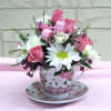 Pink and white flower arrangement in a floral teacup and saucer