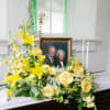 Yellow floral arrangement beside a framed photo and candles on a casket