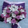 Bouquet of pink roses and white orchids wrapped in purple paper