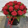 Red roses arranged in a black hatbox with a red ribbon