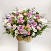 Basket arrangement of pink roses, daisies, carnations, and lavender flowers