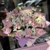 Large bouquet of pale pink roses and white orchids wrapped in lavender paper