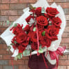 Bouquet of red roses wrapped in white paper with ribbon