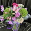 Pink and lavender floral arrangement in a glass vase with a butterfly accent