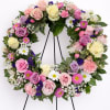 Pastel wreath of roses, daisies, carnations and filler flowers on a black easel stand