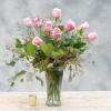 Pink roses arranged in a clear glass vase with greenery