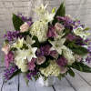 Large bouquet of white lilies, pink roses, and purple flowers in a white vase