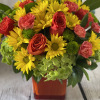 Bouquet of yellow daisies, red roses, and pink carnations in an orange vase