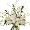 White roses and orchids in a clear glass vase