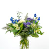 Mixed bouquet of blue, purple, and cream flowers in a clear glass jar vase